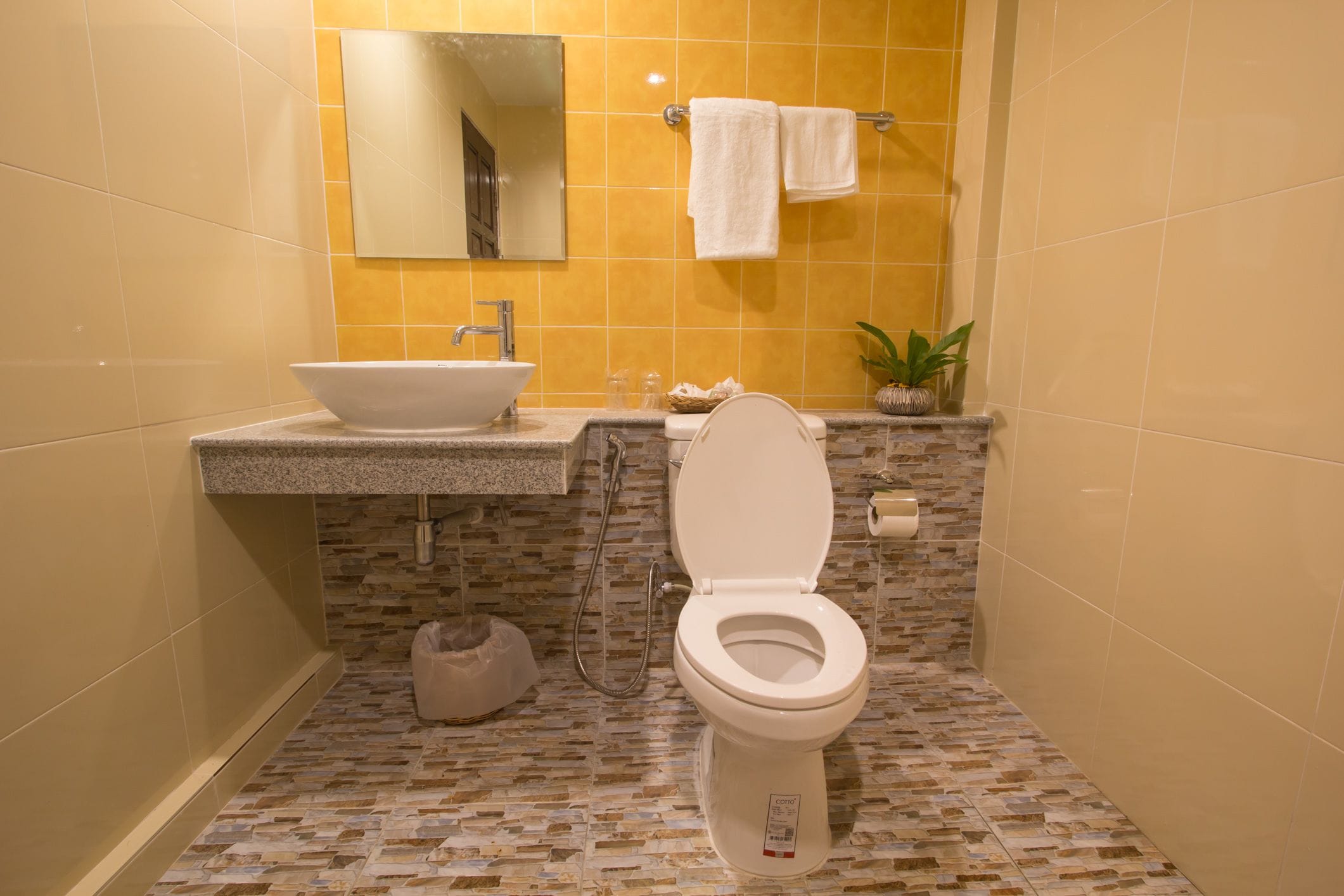 A bathroom with a white sink, a toilet, a mirror, and a towel rack.