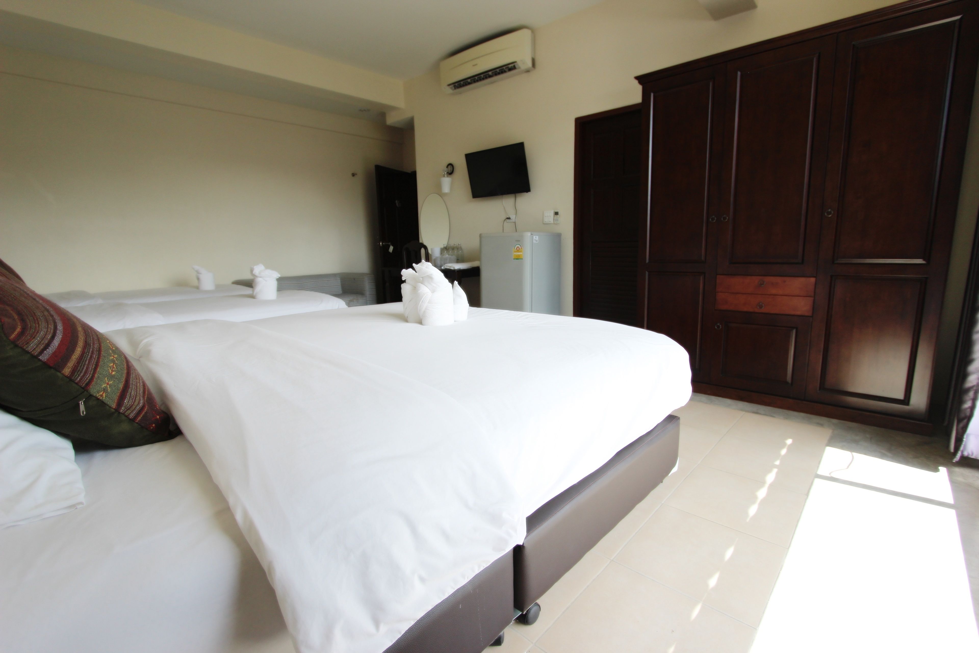Une chambre d’hôtel avec un grand lit, une armoire, une télévision et un appareil de climatisation.