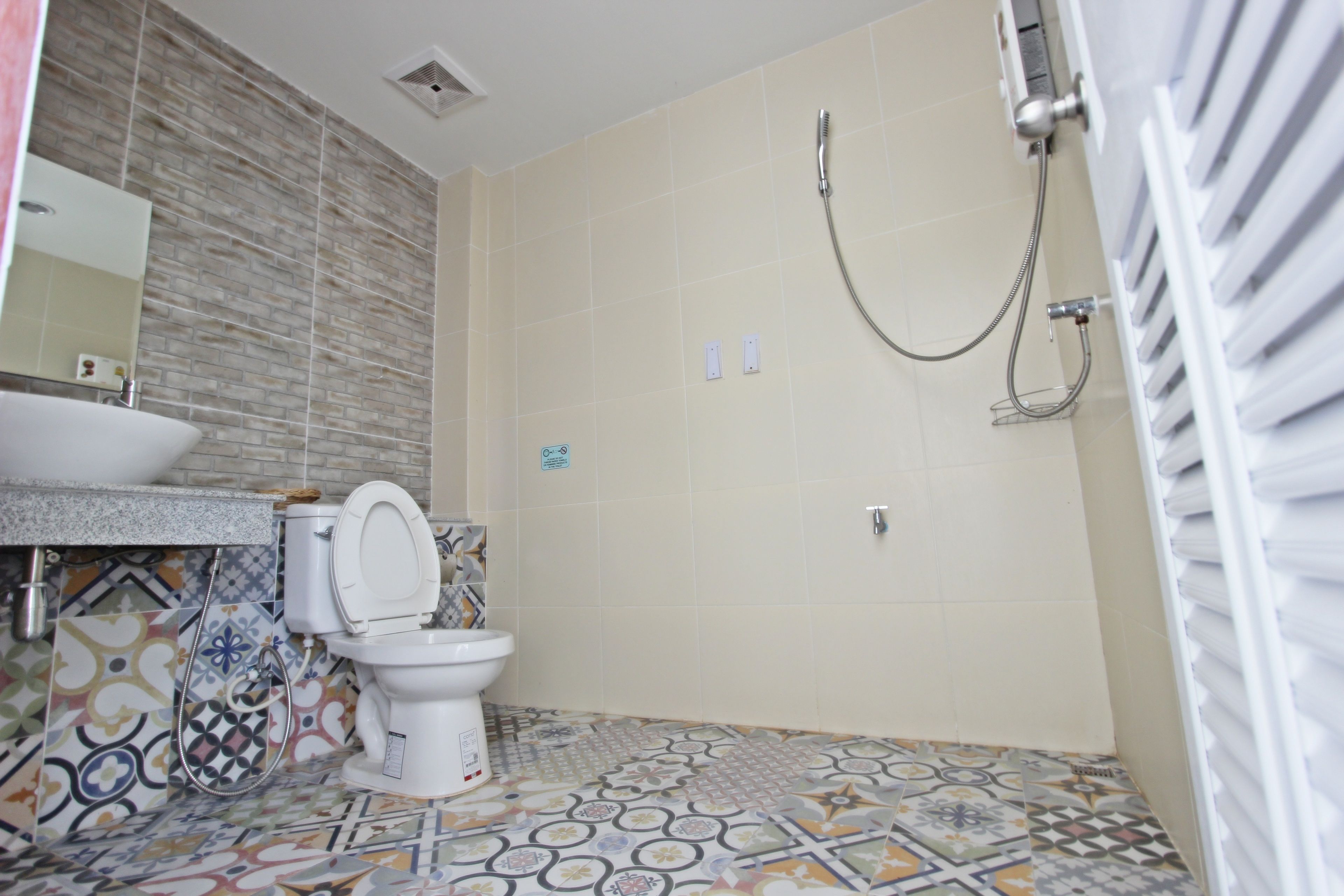 Een badkamer met betegelde vloer, een wastafel, toilet en douche.