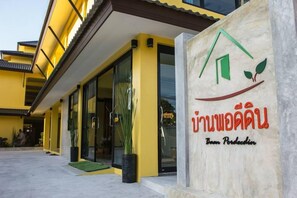 A building with a yellow facade and a sign with a green roof and leaf symbol.