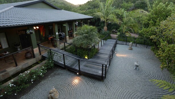 A house with a covered patio, a wooden deck, and a garden with a water feature.