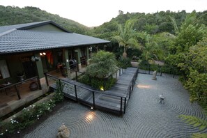 A house with a covered patio, a wooden deck, and a garden with a water feature. - Shangri-La Manor - Adults Only (Wilderness)