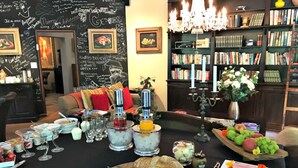 A cozy living room with a fireplace, a bookshelf filled with books, and a dining area with a table set for a meal.