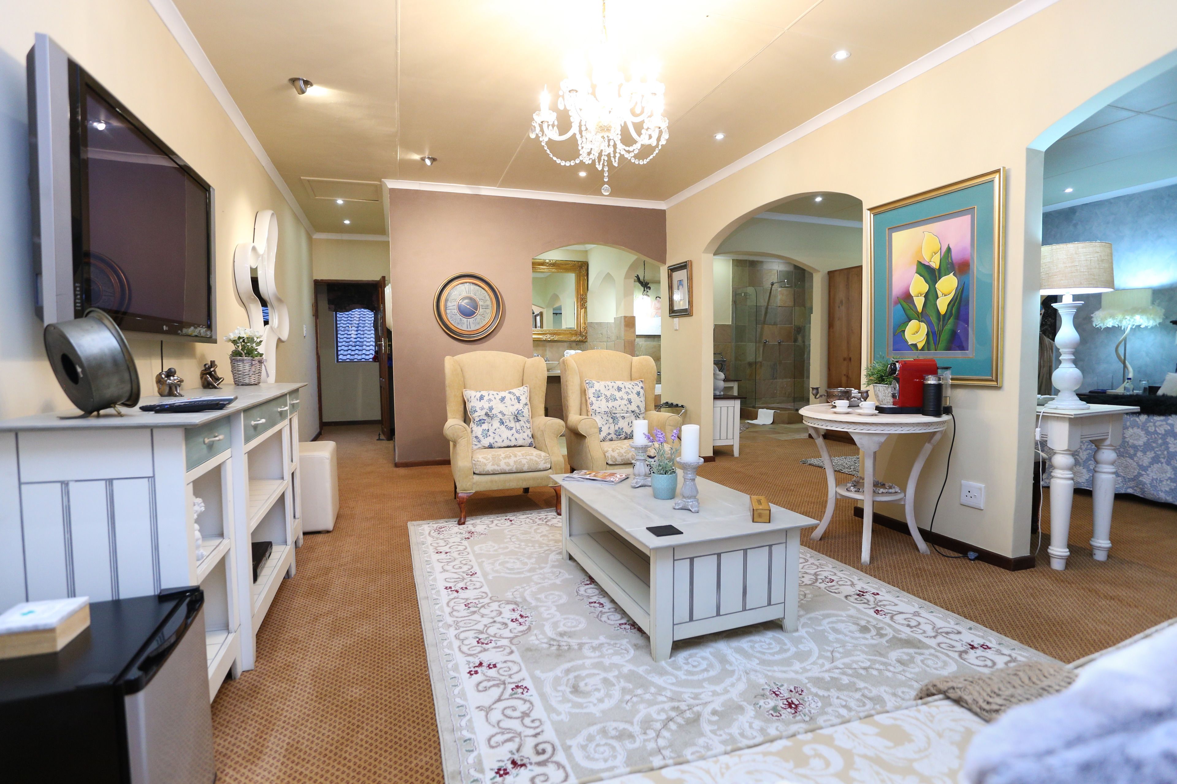 A modern living room with a flat-screen TV, comfortable seating, a chandelier, and a decorative rug.