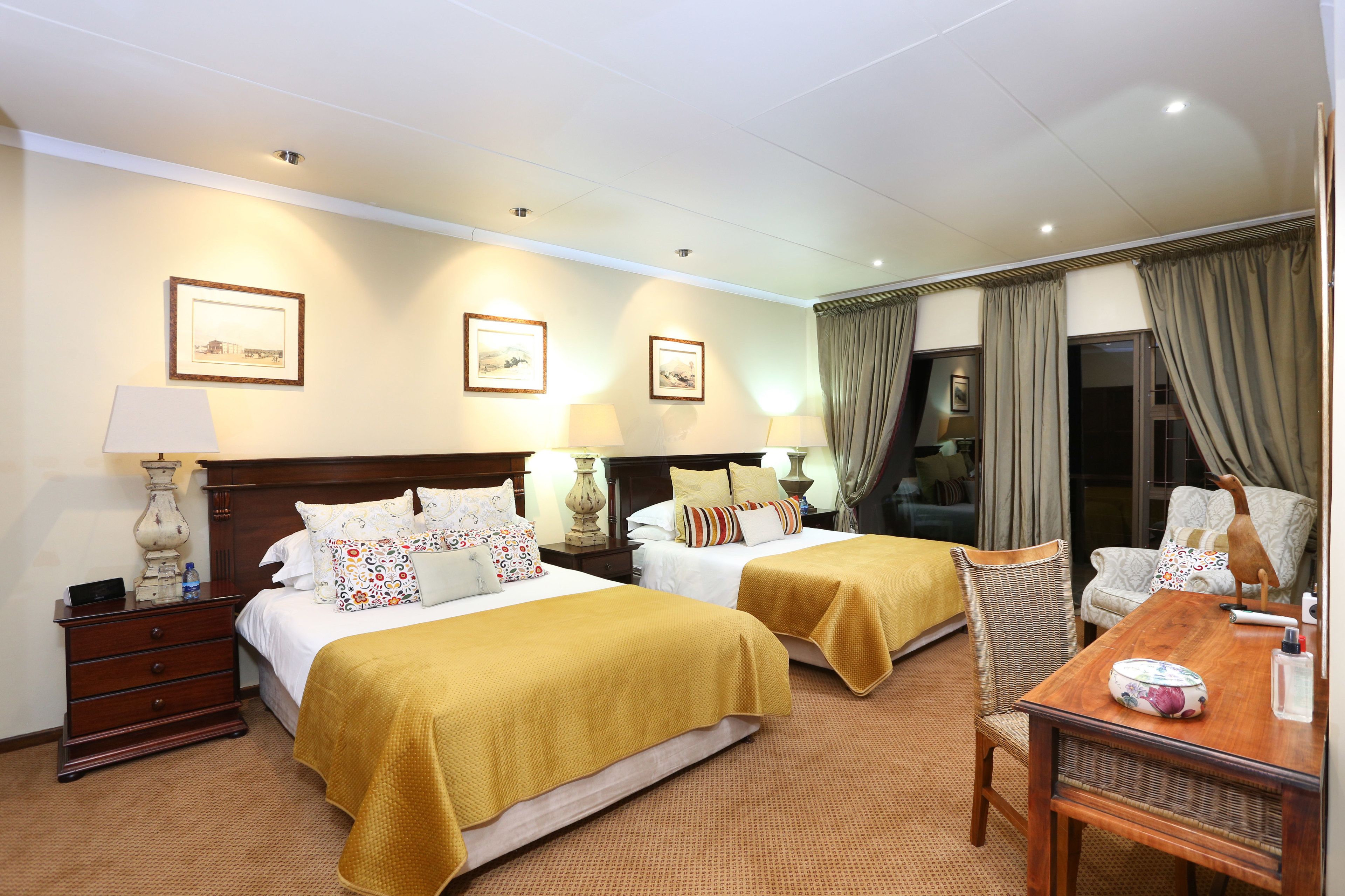 Ein Hotelzimmer mit zwei Betten, einem Holznachttisch, einem Tisch und einem Stuhl.
