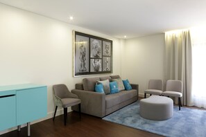 Una sala de estar moderna con un sofá gris, dos sillones, un tapete azul y un aparador azul claro.