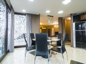 A modern dining area with a round table, black chairs, and a chandelier. - Tbilisi Core: Leo (Tbilisi)