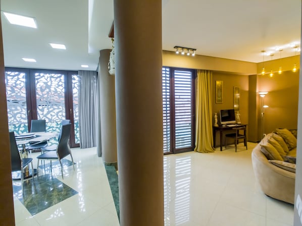 A modern hotel room with a dining area, a sofa, and a desk with a computer. - Tbilisi Core: Leo (Tbilisi)