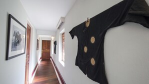A hallway with wooden flooring, framed pictures on the walls, and a black garment hanging on the right. - The Belle Rive Boutique Hotel (Luang Prabang)
