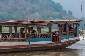 A traditional boat with passengers, featuring a covered deck and ornate railings.