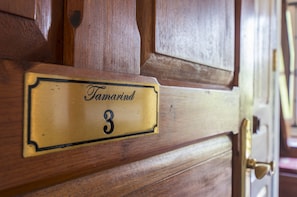 A brass nameplate with the name "Tamarind" and the number "3" on a wooden door.
