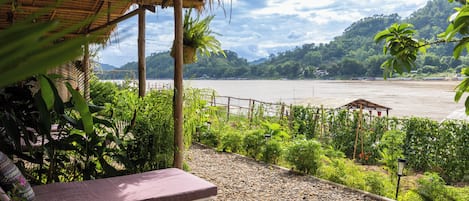 Un espacio de estar al aire libre con techo y vistas a un río y colinas.