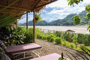 A covered outdoor seating area with a view of a river and hills. - The Belle Rive Boutique Hotel (Luang Prabang)