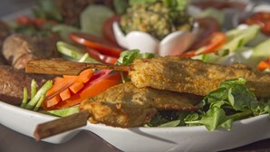 A plate of food with skewered meat, vegetables, and a salad. - The Belle Rive Boutique Hotel (Luang Prabang)