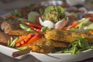 A plate of food with skewered meat, vegetables, and a salad.