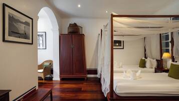 A four-poster bed with white linens and a canopy, a wooden wardrobe, and a framed picture on the wall.