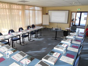 A conference room with a long table, chairs, a projector screen, and presentation materials. - Pressoir Hôtel (Saint-Calais)
