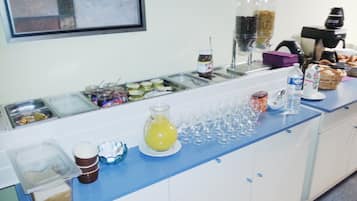 A buffet setup with various food items, a coffee machine, and a juice dispenser.