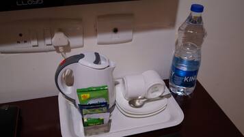 Una bandeja con una tetera, una taza, una cuchara, una botella de agua y pañuelos desechables.