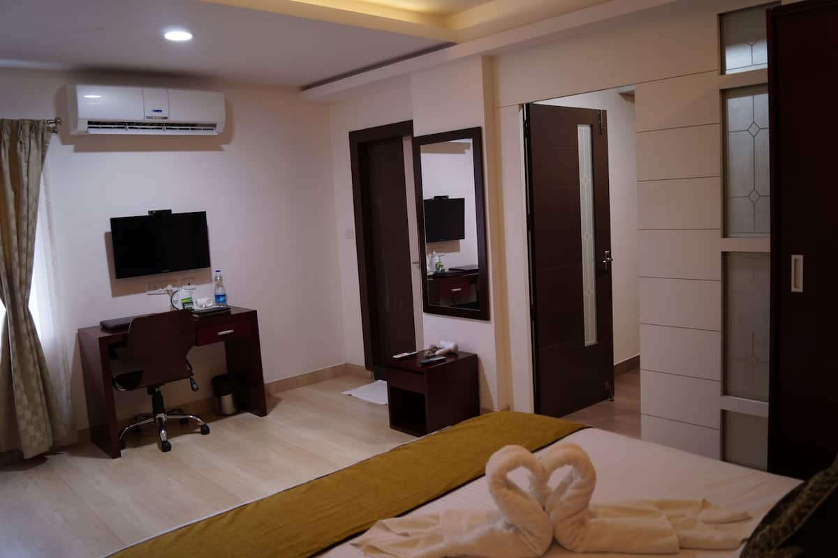 A hotel room with a bed, a desk, a chair, a television, and a wardrobe.