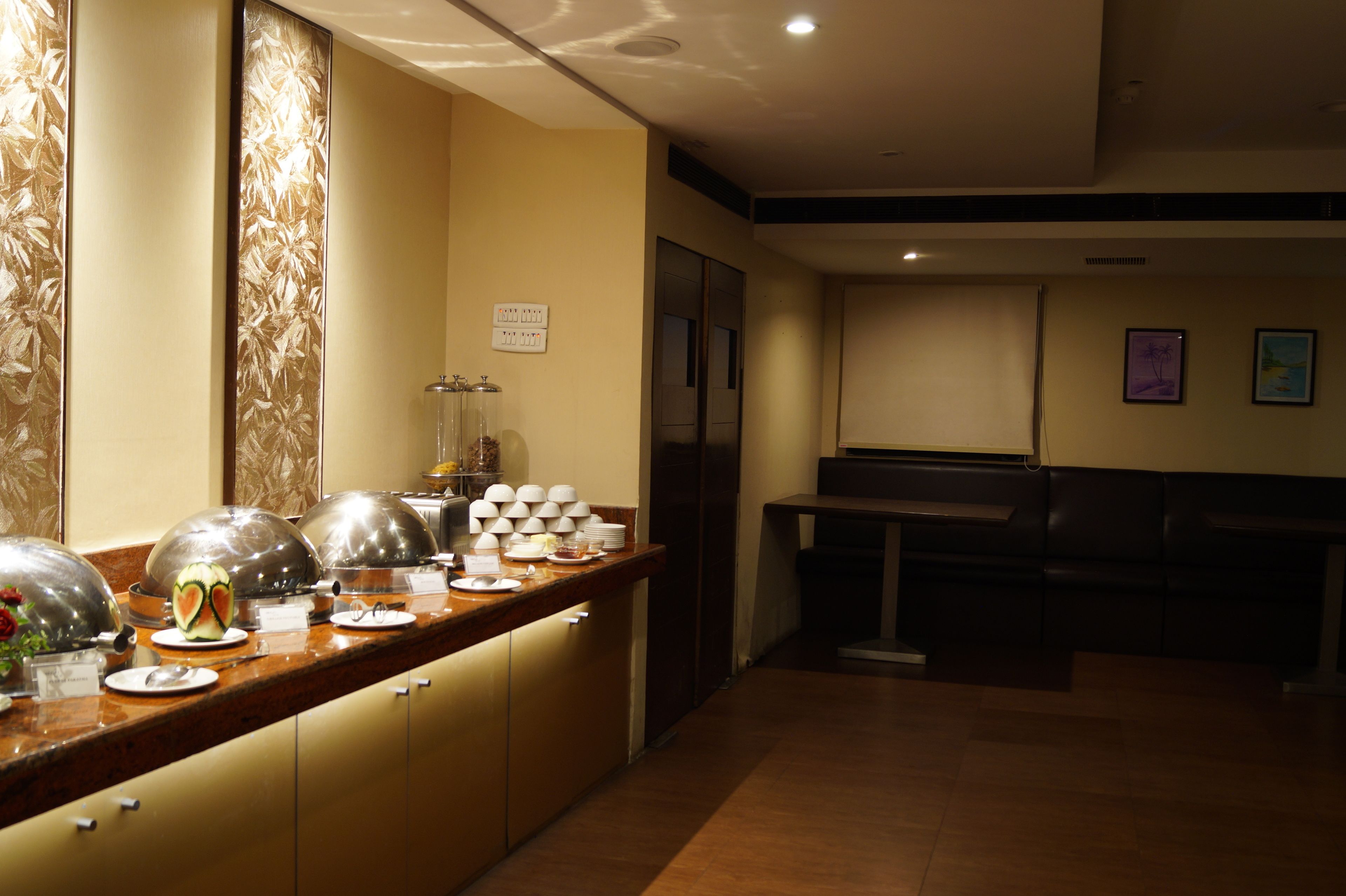 A hotel reception area with a buffet counter, a refrigerator, and a seating area.
