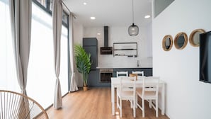 A modern kitchen with a dining area, wooden flooring, and a large window with curtains. - SmartRental Madrid Puerta del Sol (Madrid)
