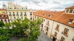 A courtyard with trees, a fountain, and buildings with balconies and windows. - SmartRental Madrid Puerta del Sol (Madrid)