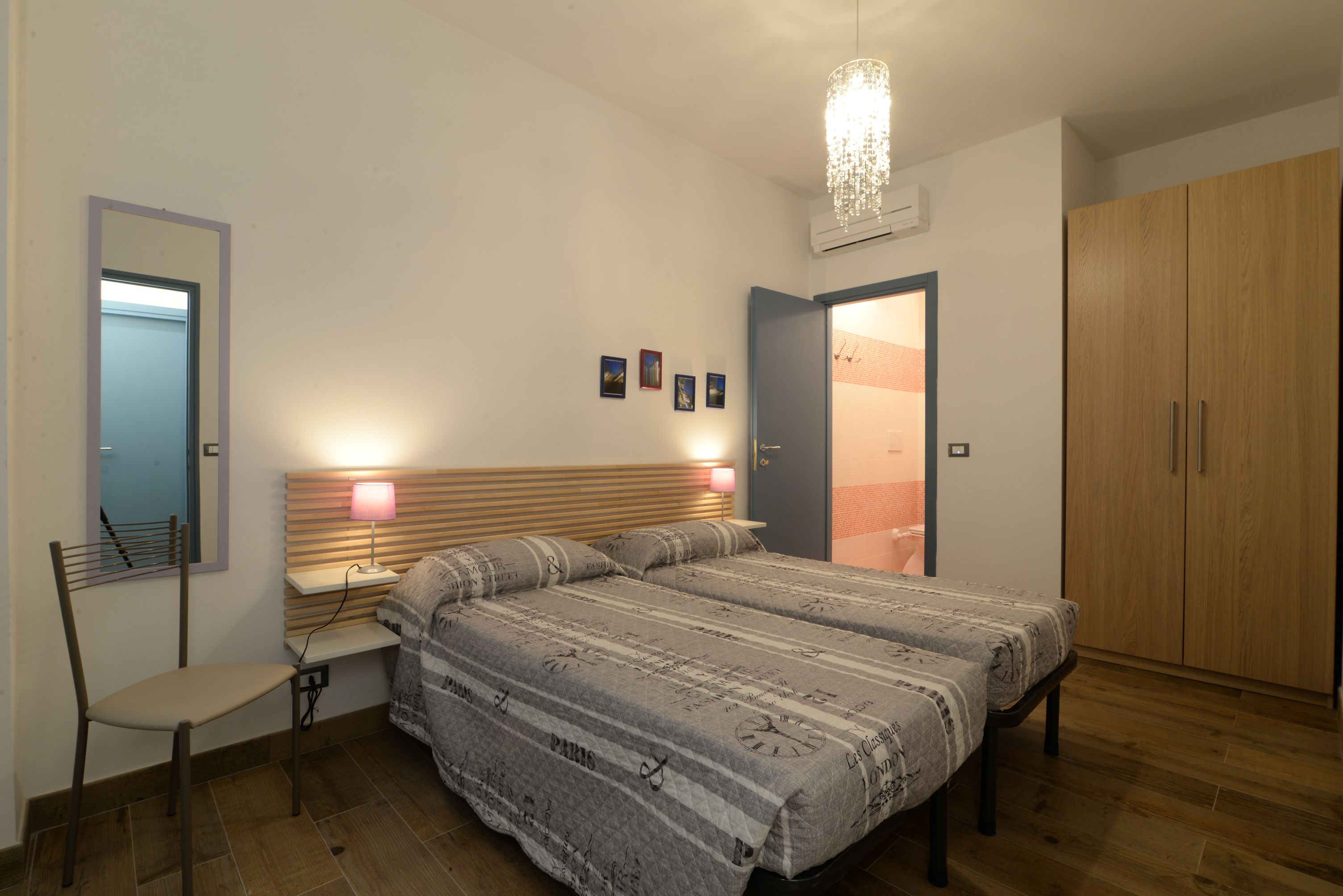 Quarto com cama, uma cadeira, guarda-roupa e espelho.