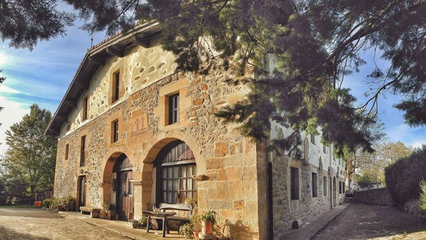 Ein Steinhaus mit Rundbogenfenstern und einem Kreuzzeichen, was auf eine historische oder religiöse Bedeutung hindeutet.