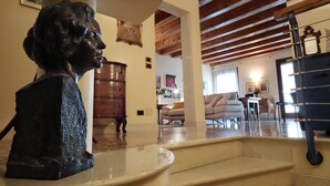 Una scultura in una stanza con travi in legno, una scala e una zona living con mobili.
