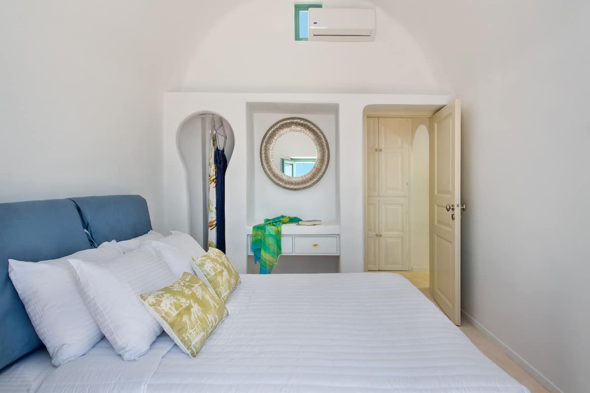 A bedroom with a bed, a dresser, a mirror, and a door.