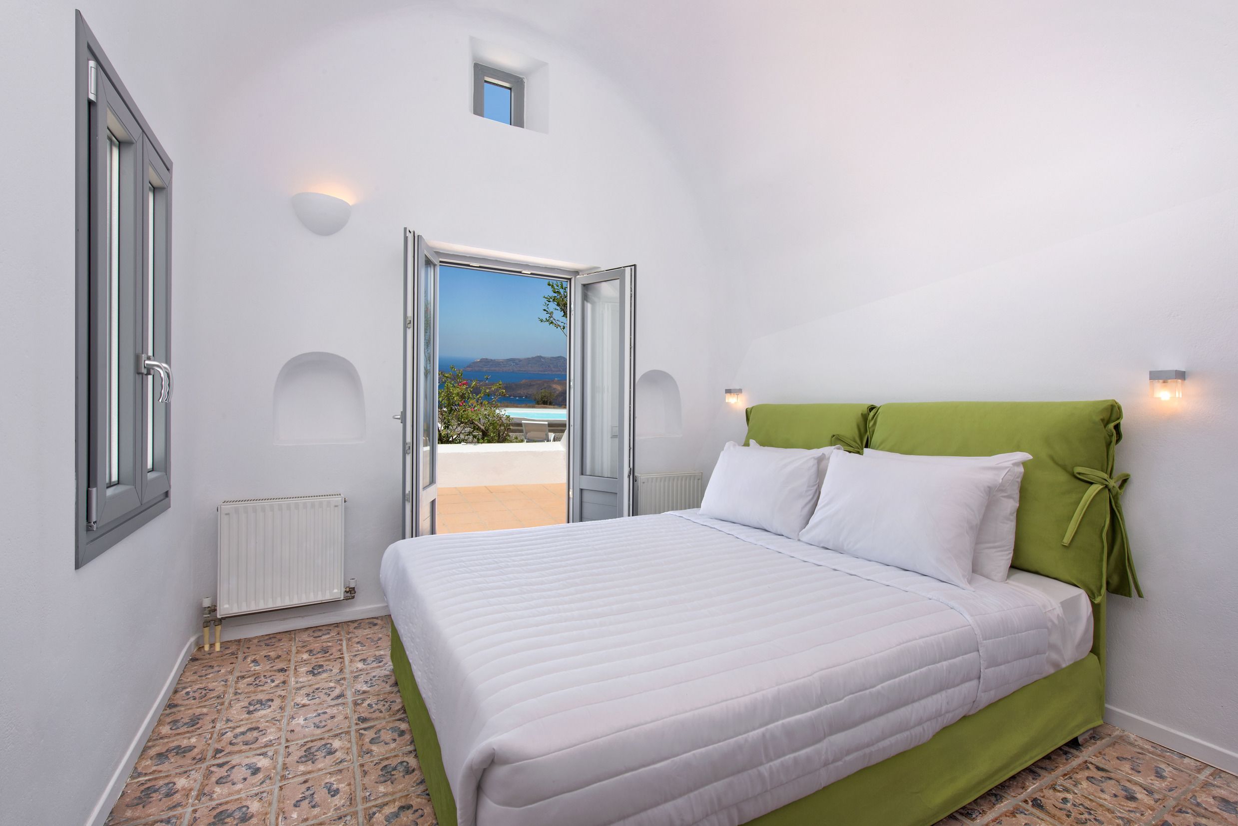 Una camera da letto con un letto, vista attraverso una porta aperta e una piccola finestra sul tetto.
