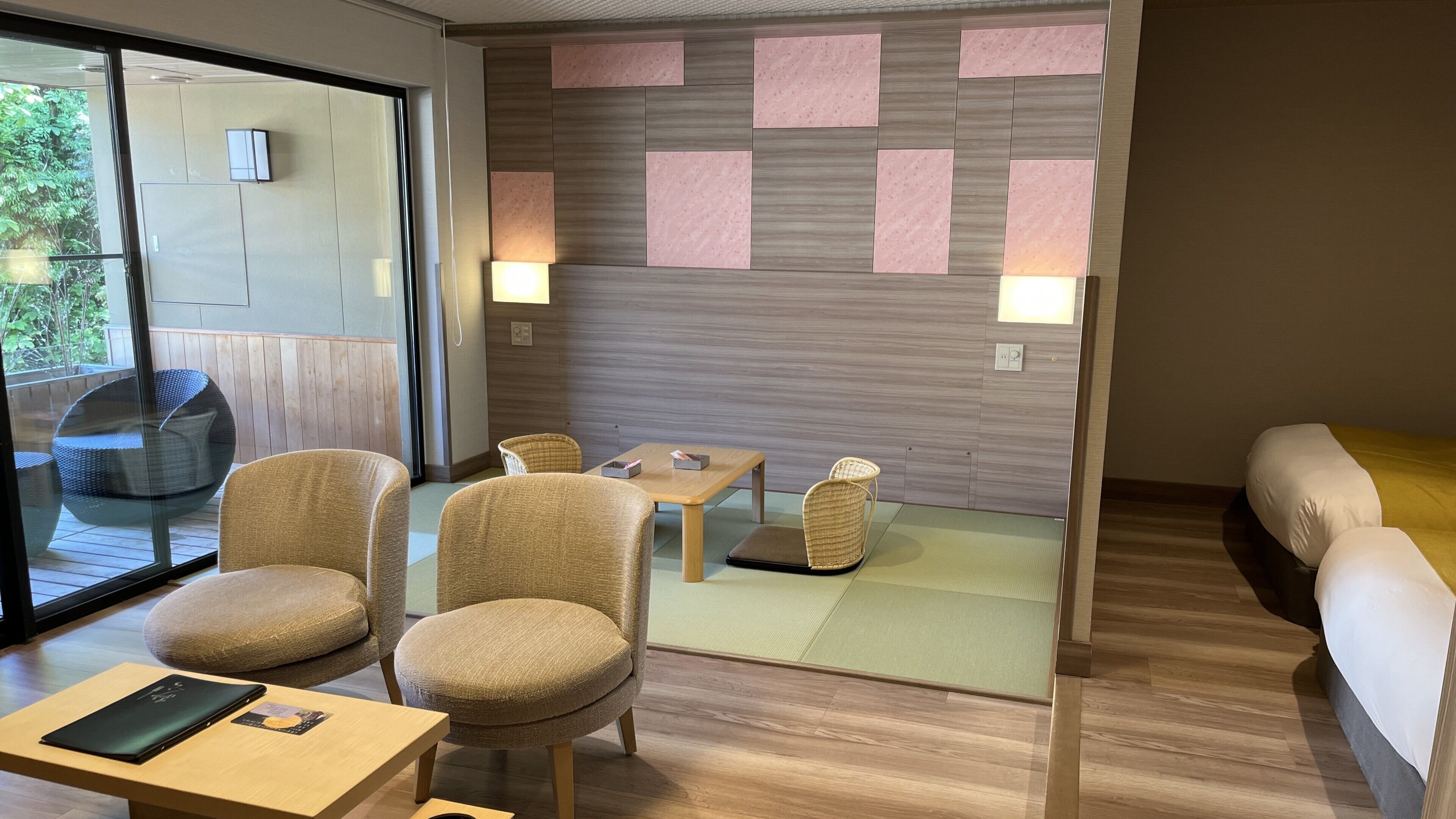 Ein modernes Zimmer mit Holzboden, einer Couch, zwei Stühlen, einem kleinen Tisch und einer Glastür, die nach draußen führt.