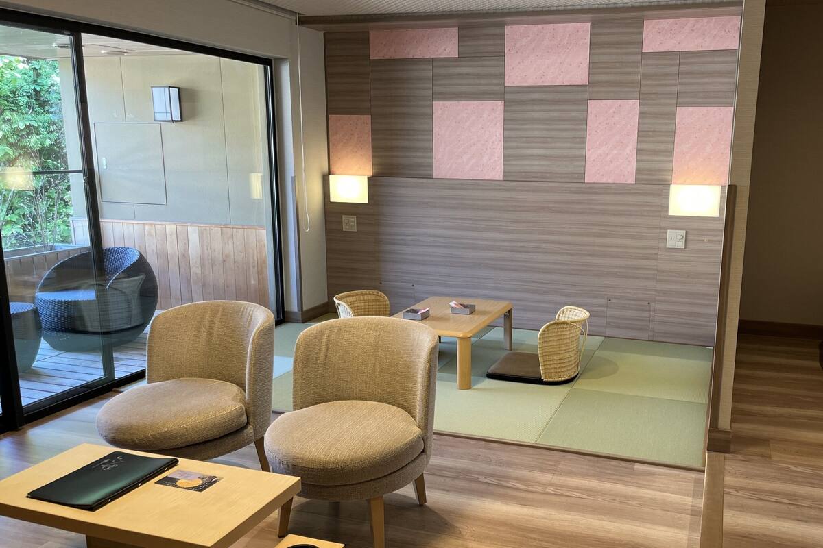 A modern room with a wooden floor, a sofa, two chairs, a small table, and a glass door leading outside.