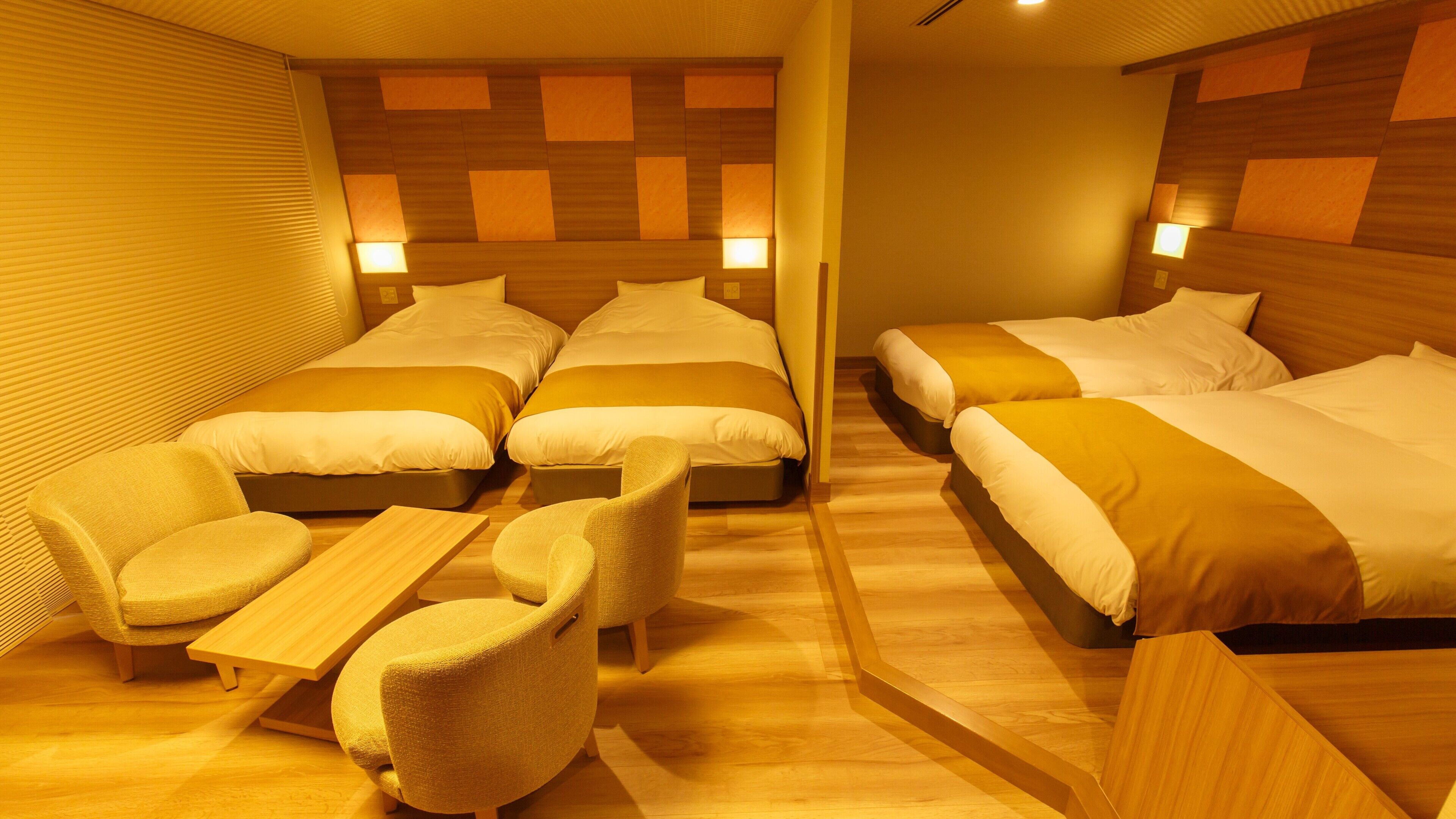 Ein Hotelzimmer mit vier Einzelbetten, einer Schlafcouch und einem kleinen Tisch.
