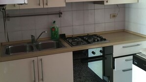 A kitchen with white cabinets, a stainless steel sink, a gas stove, and a dishwasher. - Appartamenti Soperga (Milan)