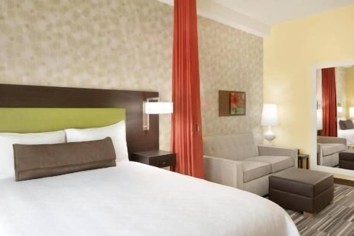 Une chambre d’hôtel avec un grand lit, un canapé, une petite table et un miroir.