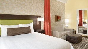 Habitación de hotel con una cama grande, un cabecero verde, un sofá, una mesita y un espejo.