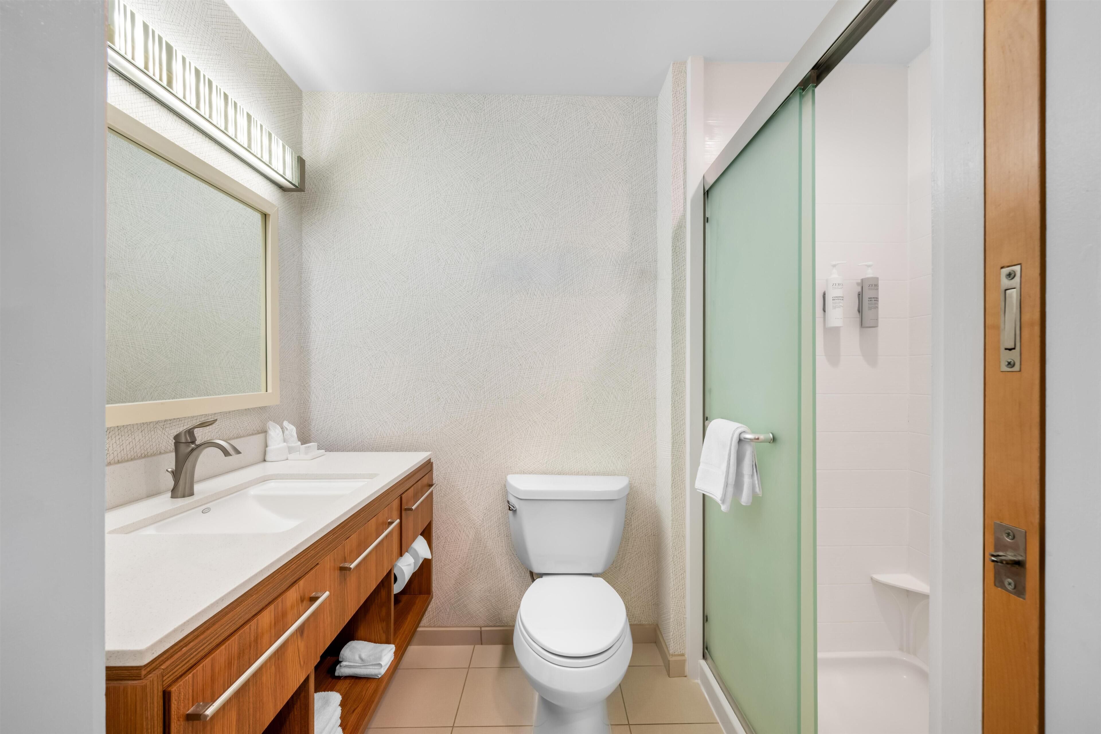 Ein Badezimmer mit einem Doppelwaschbecken, Toilette und einer Duschkabine aus Glas.