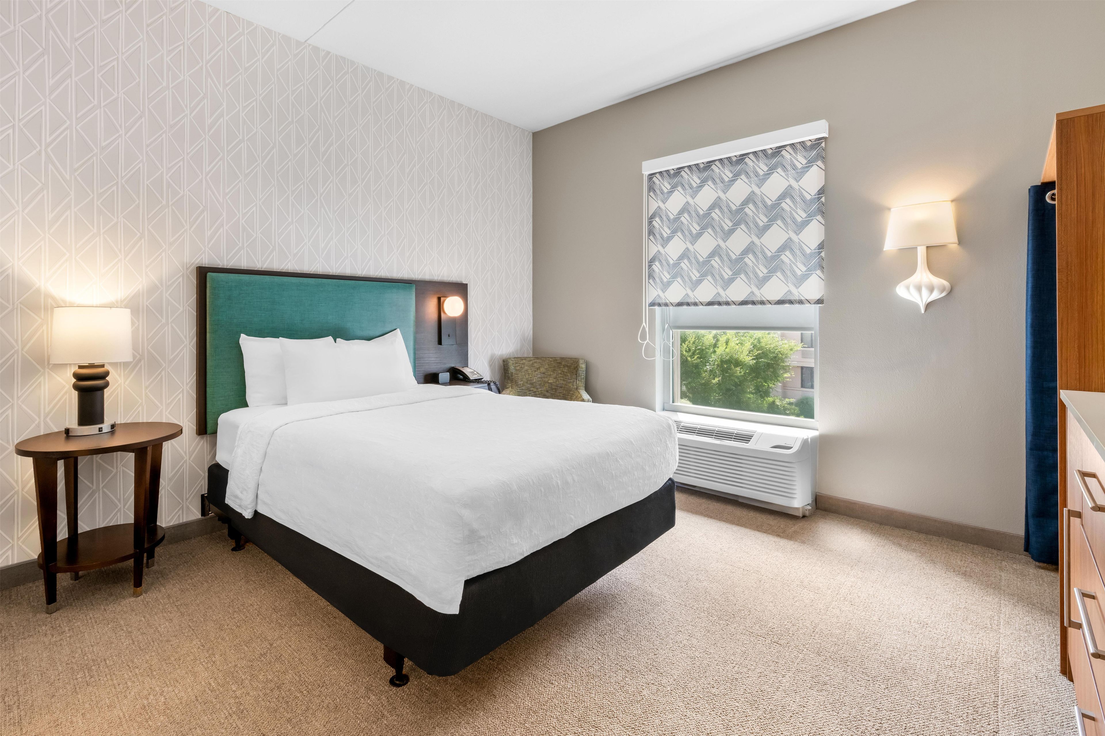 Een hotelkamer met een bed, nachtlampjes, een raam met uitzicht en een radiator.