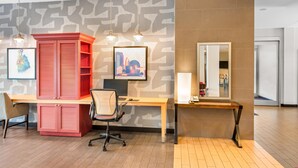 Un espacio de oficina moderno con un escritorio de madera, un armario rojo y un espejo grande.