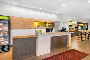 Een hotel receptie met een balie, een koelkast en een zithoek.