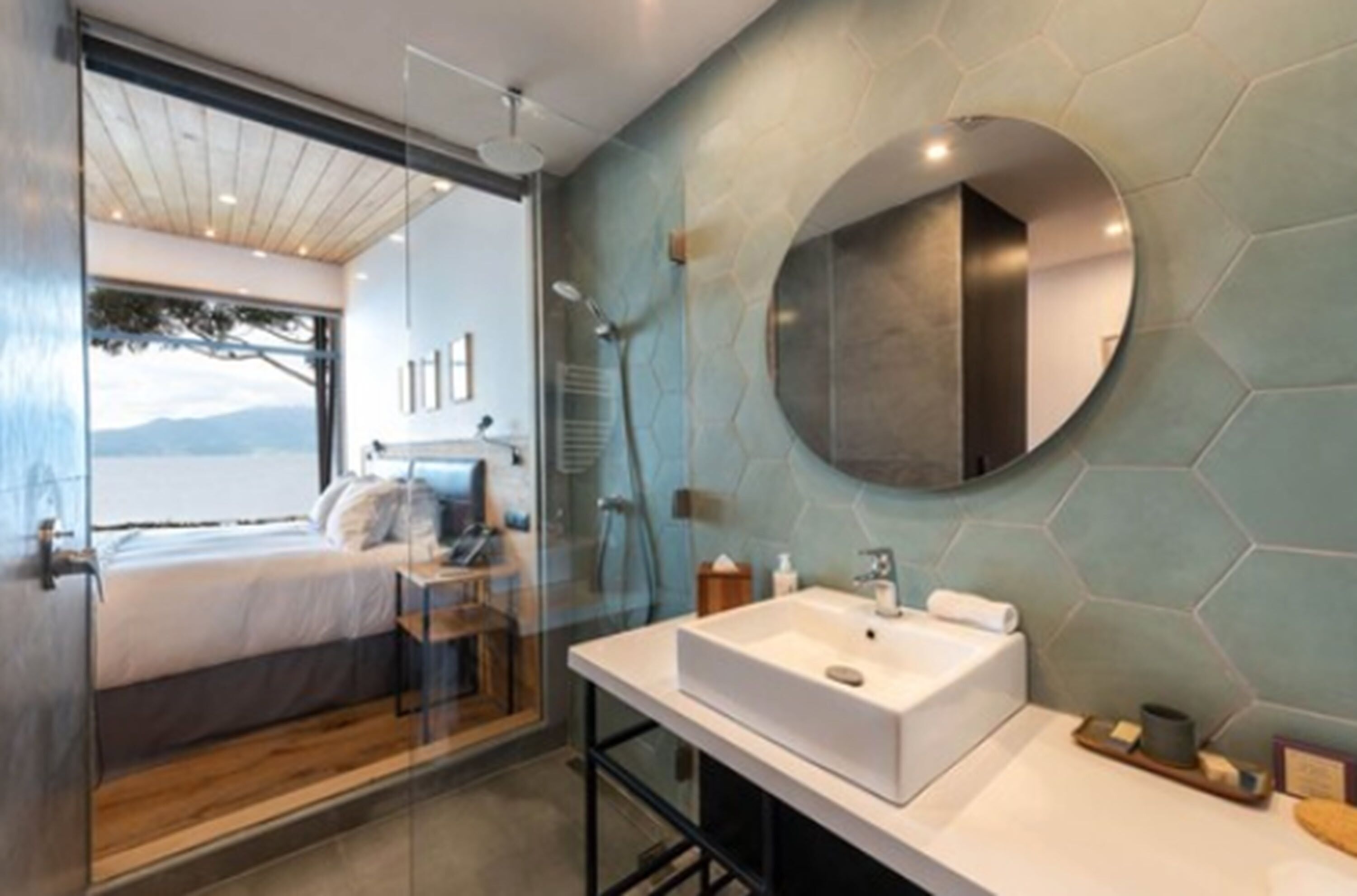 A modern bathroom with a large mirror, a white sink, and a glass shower enclosure.