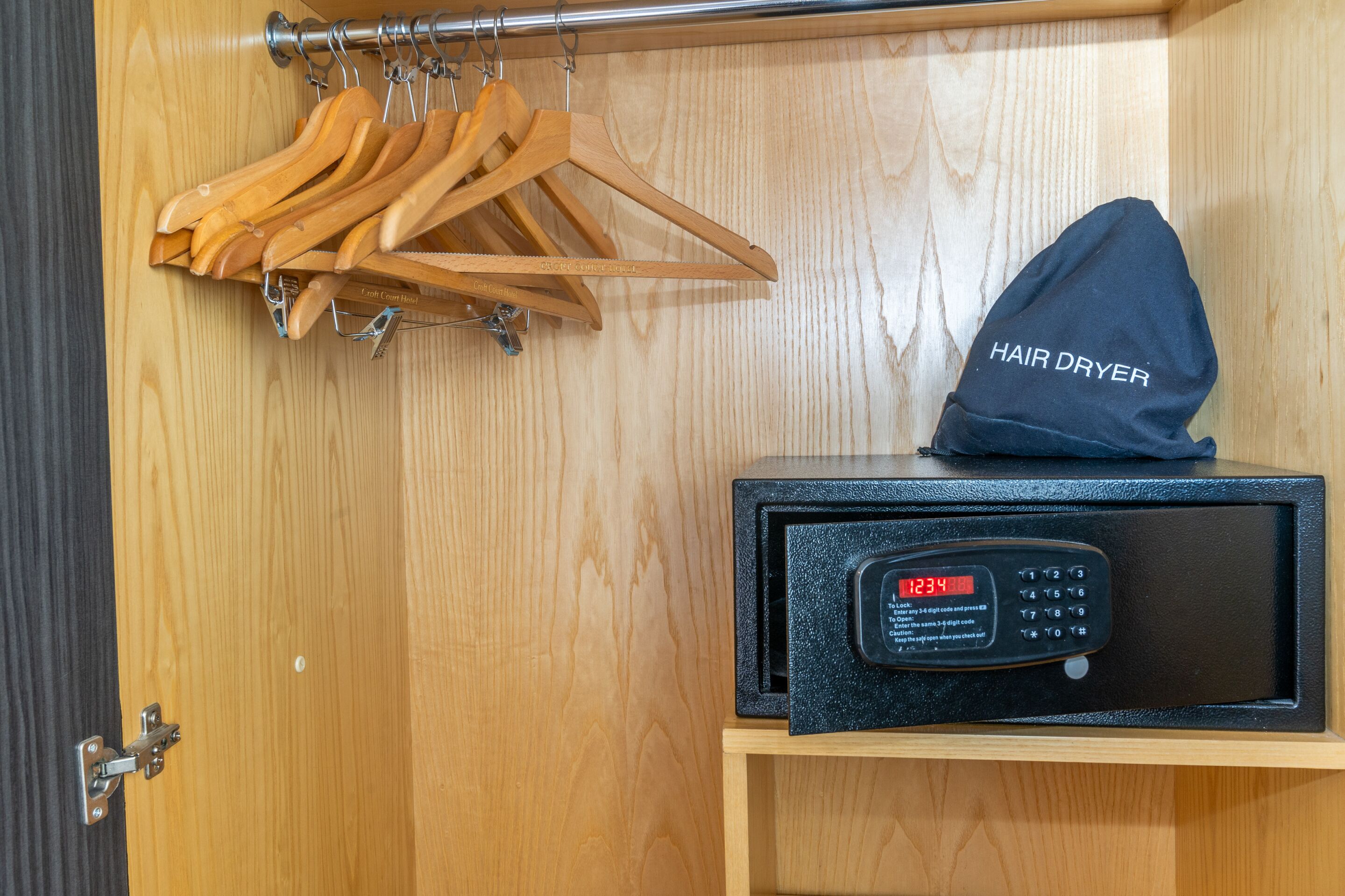 A wooden wardrobe with a hair dryer and a digital lock.