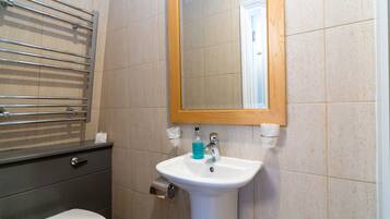 A bathroom with a white sink, a mirror, and a towel rack.