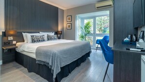 Ein modernes Schlafzimmer mit einem großen Bett, Nachttischen, einem Schreibtisch und Blick ins Freie.