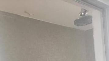 Shower area features a ceiling-mounted showerhead and a bench for seating.