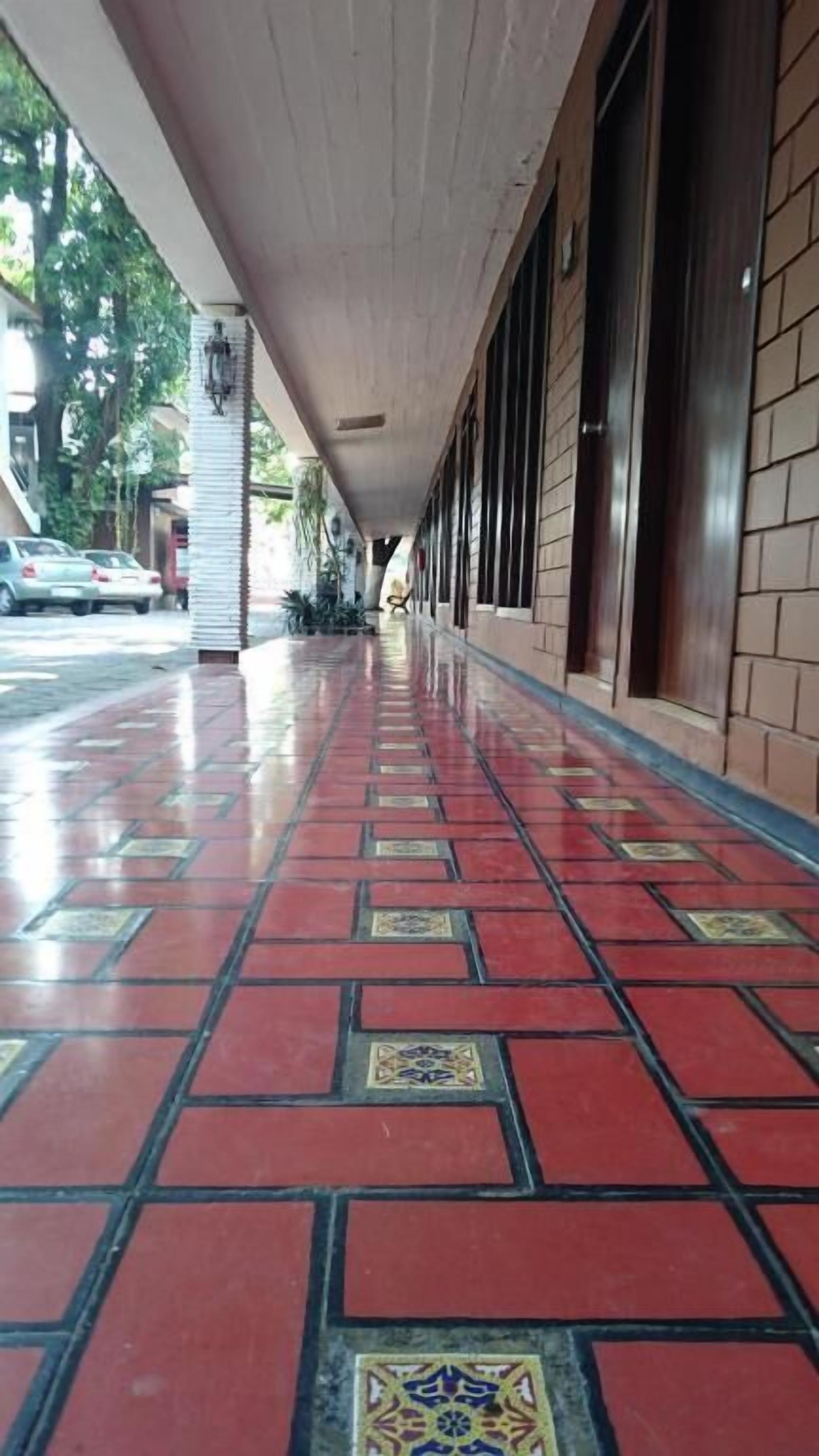 Un pasillo con suelo de baldosas, una cubierta protectora y una pared de ladrillo.