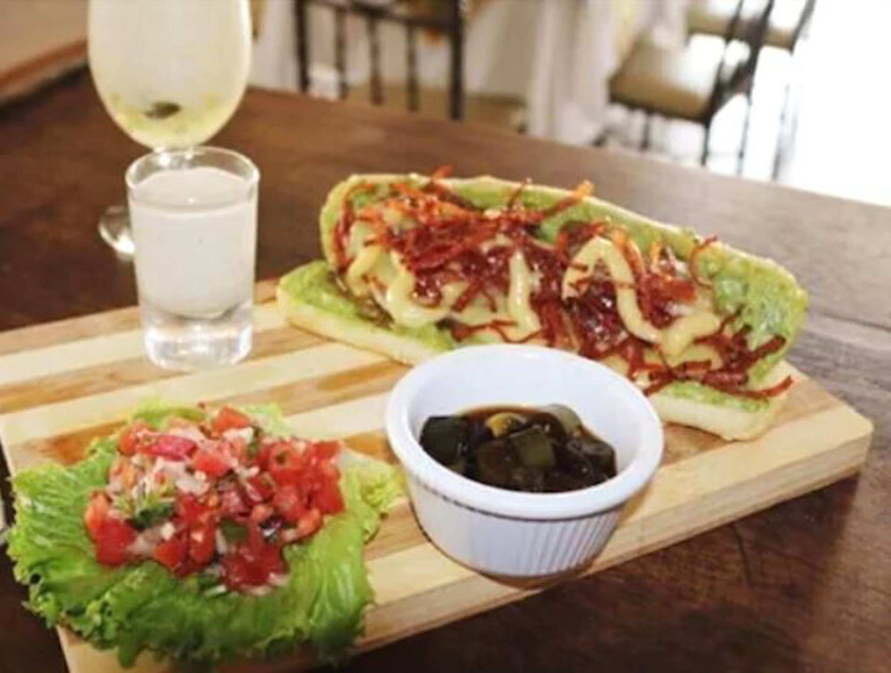 A meal with a sandwich and a side salad on a wooden board.