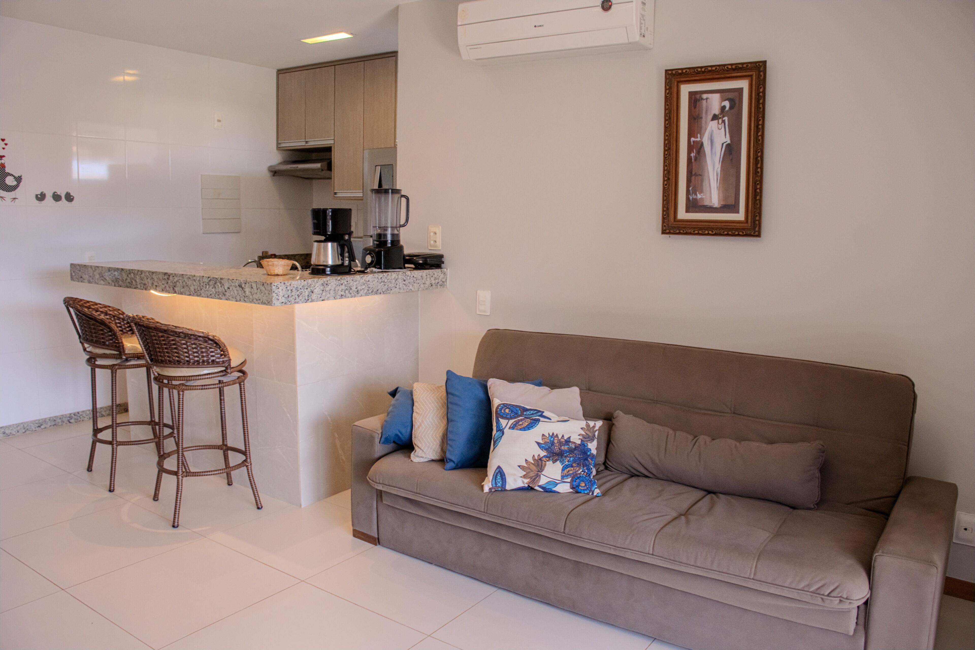 A modern kitchen with a built-in island, bar stools, and a sofa with decorative pillows.